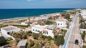 A coastal residential area with white buildings, a blue road, and a view of the sea. - VILLA SUNSET - Seafront (Torre Suda)