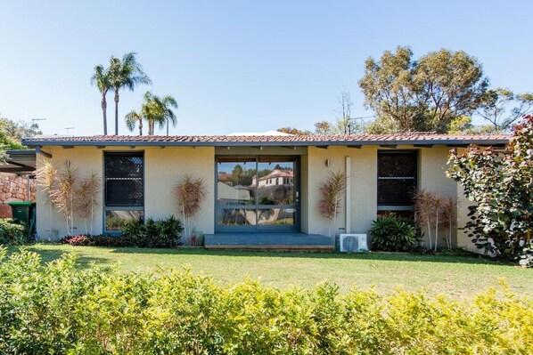 A modern two-story house with a tiled roof, large windows, and a well-maintained lawn.