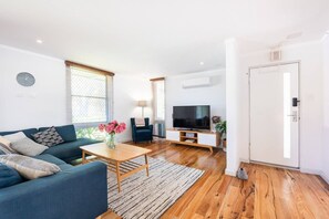 A modern living room with a sofa, coffee table, TV, and a door.