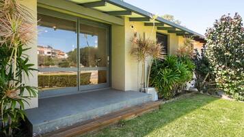 A modern house with a covered porch, sliding glass doors, and a well-maintained garden.