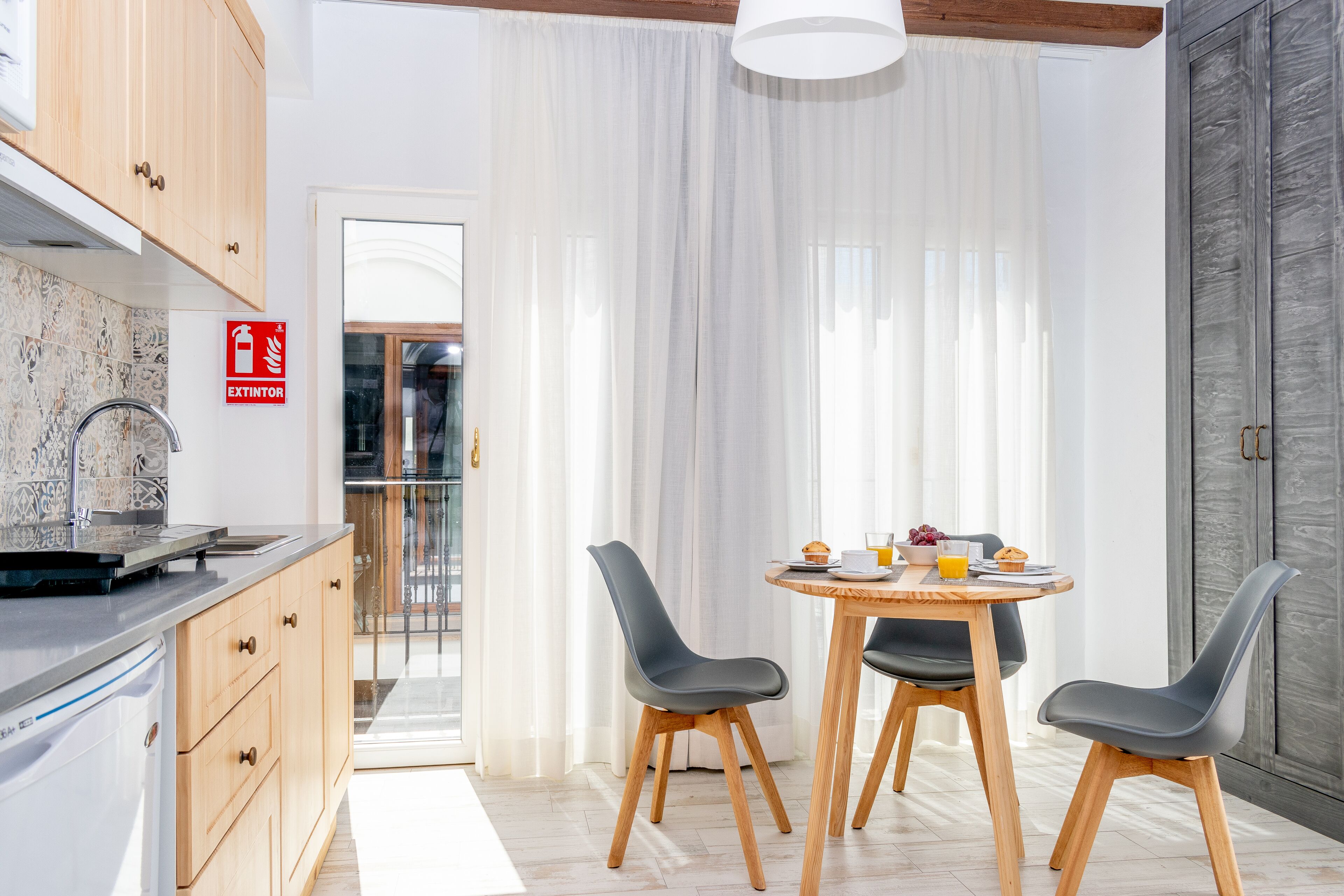 Una cocina moderna con armarios de madera, un lavamanos de acero inoxidable y una zona de desayuno con mesa y sillas.