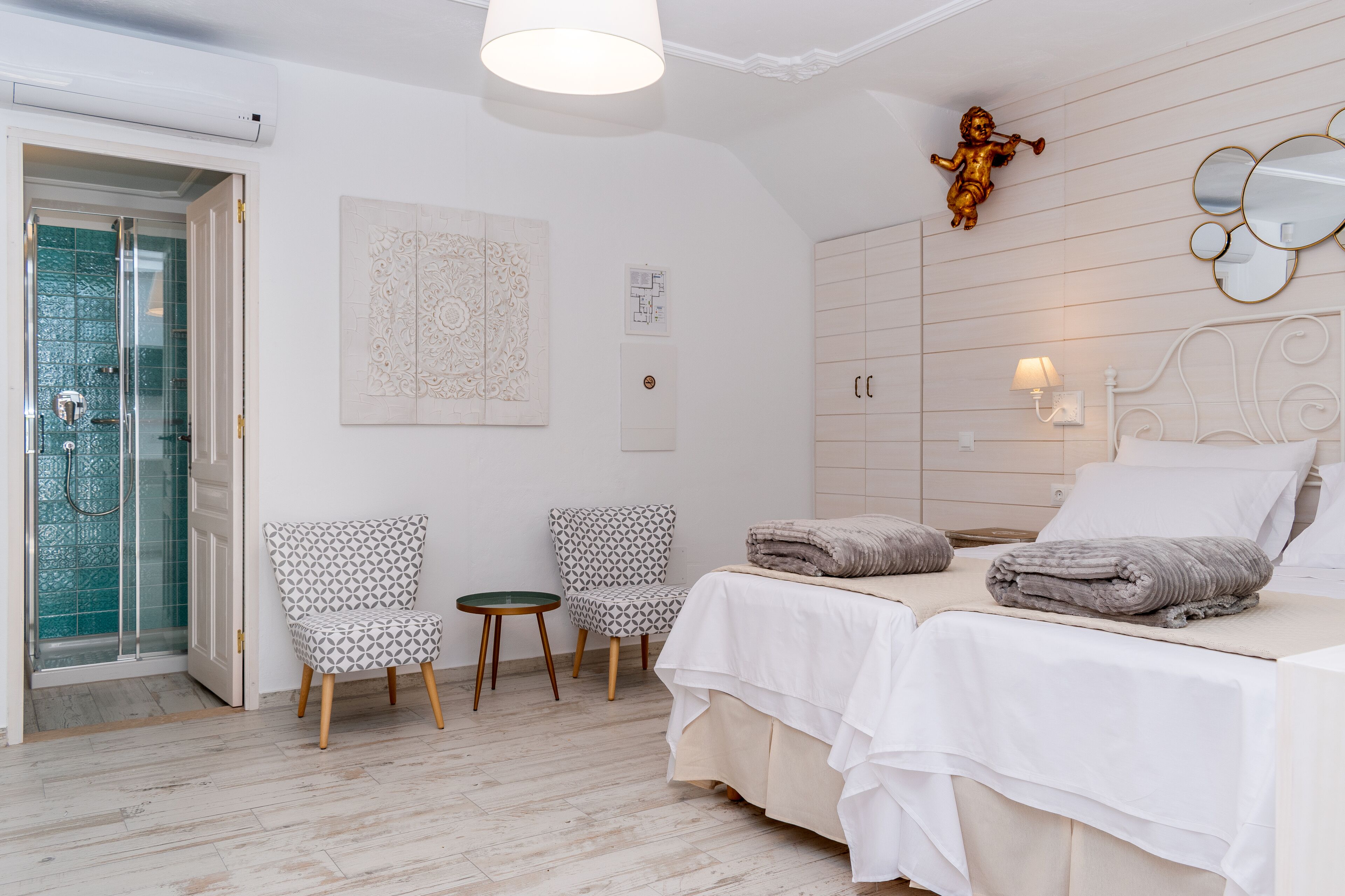 Una habitación de hotel con una cama, dos sillas, una mesita pequeña y un área de ducha.