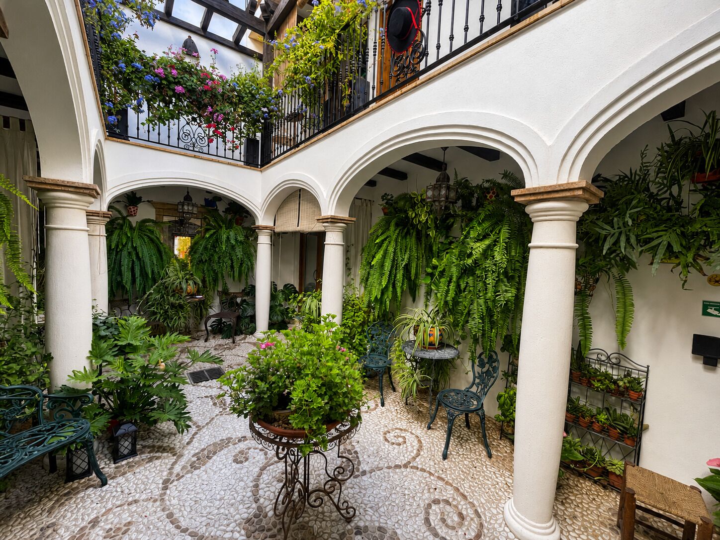 A courtyard with arches, potted plants, and a tiled floor.