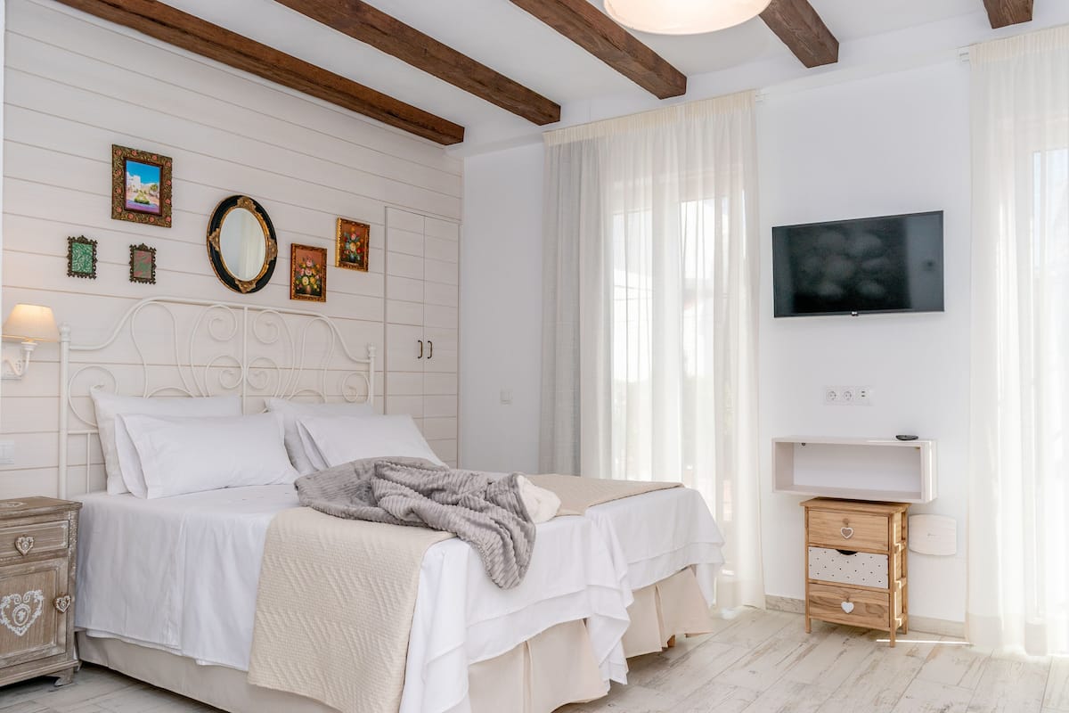 A bedroom with a bed, bedside tables, a TV, and wall decorations.