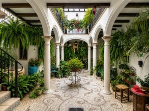 A courtyard with arches, potted plants, and a tiled floor. - Casa del Patio - Boutique Apartments (Estepona)