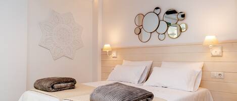 Een hotelkamer met twee bedden, een decoratief wandobject en wandlampen.