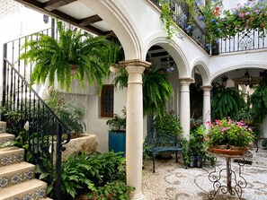 A courtyard with a staircase, columns, potted plants, and a table. - Casa del Patio - Boutique Apartments (Estepona)