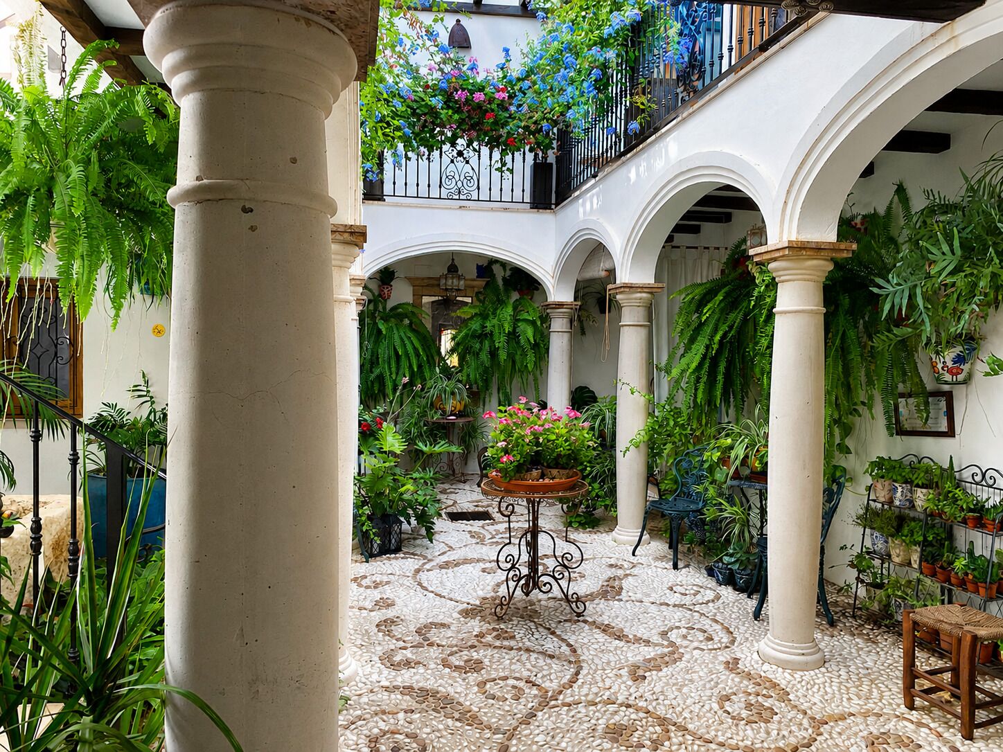 A courtyard with arches, columns, and hanging plants.