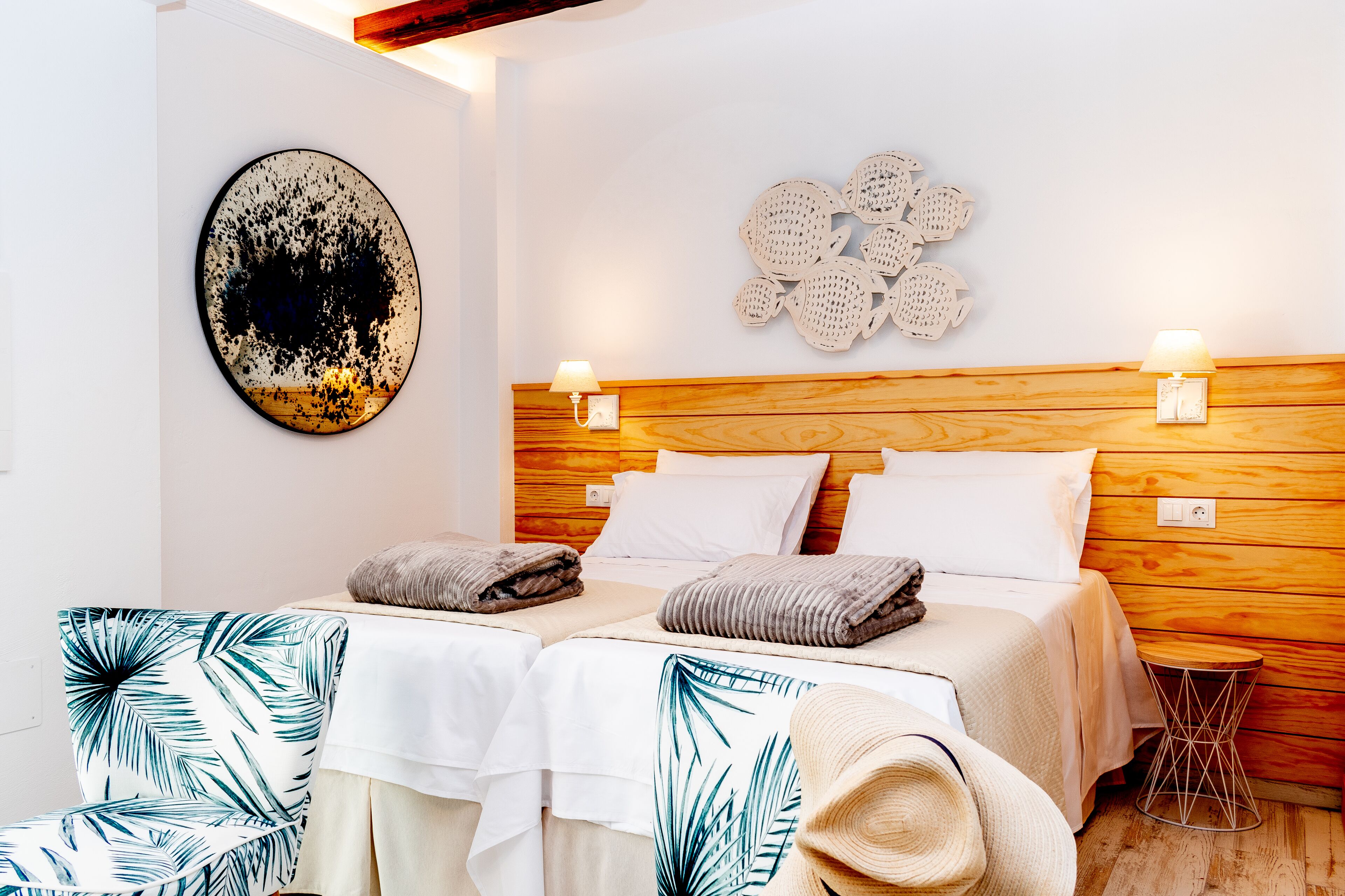A double bed with two bedside tables, a wall-mounted light fixture, and a decorative wall piece.