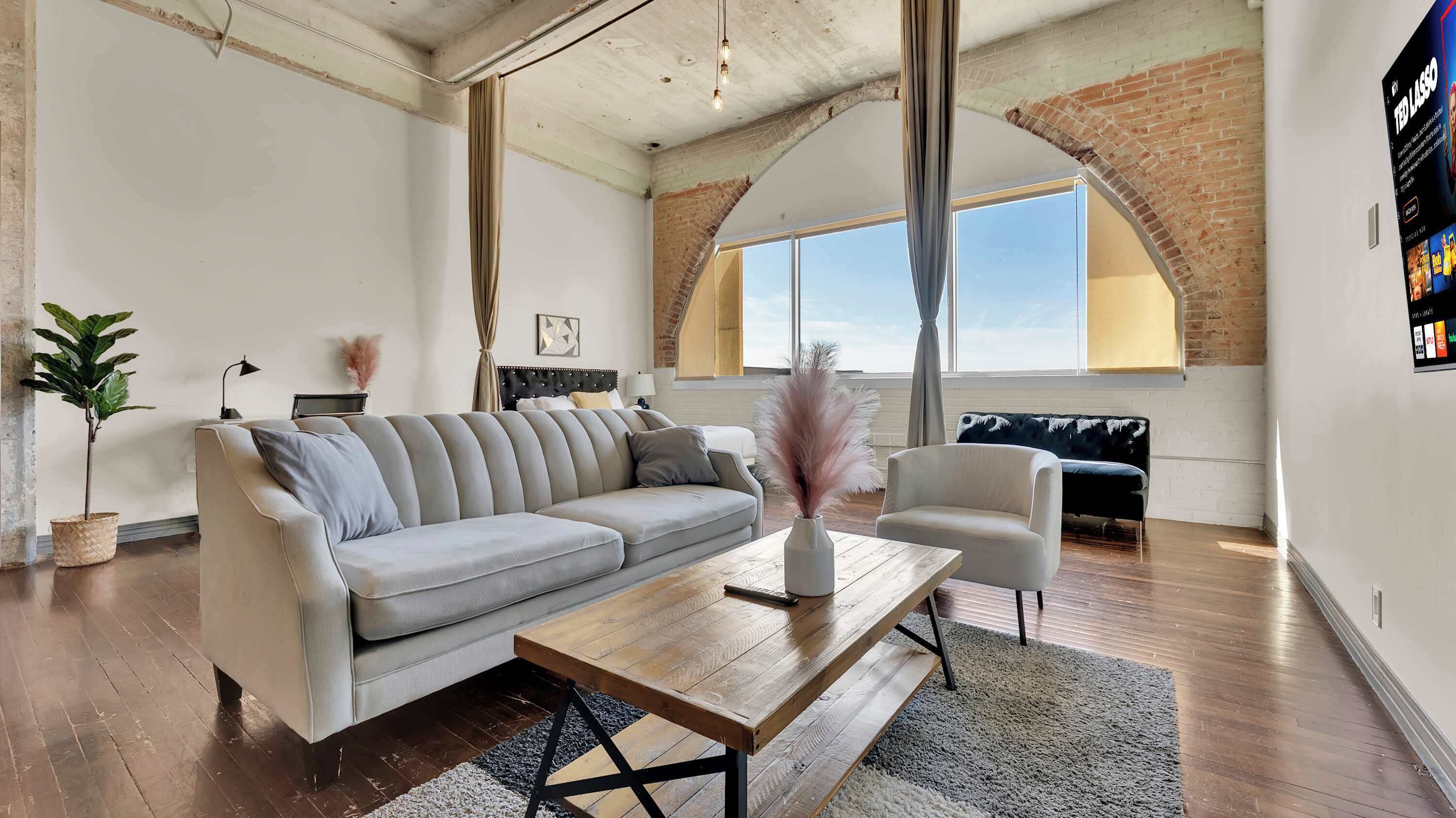 Ein großzügiges Wohnzimmer mit einer großen Couch, einem Couchtisch und einem Blumentopf.