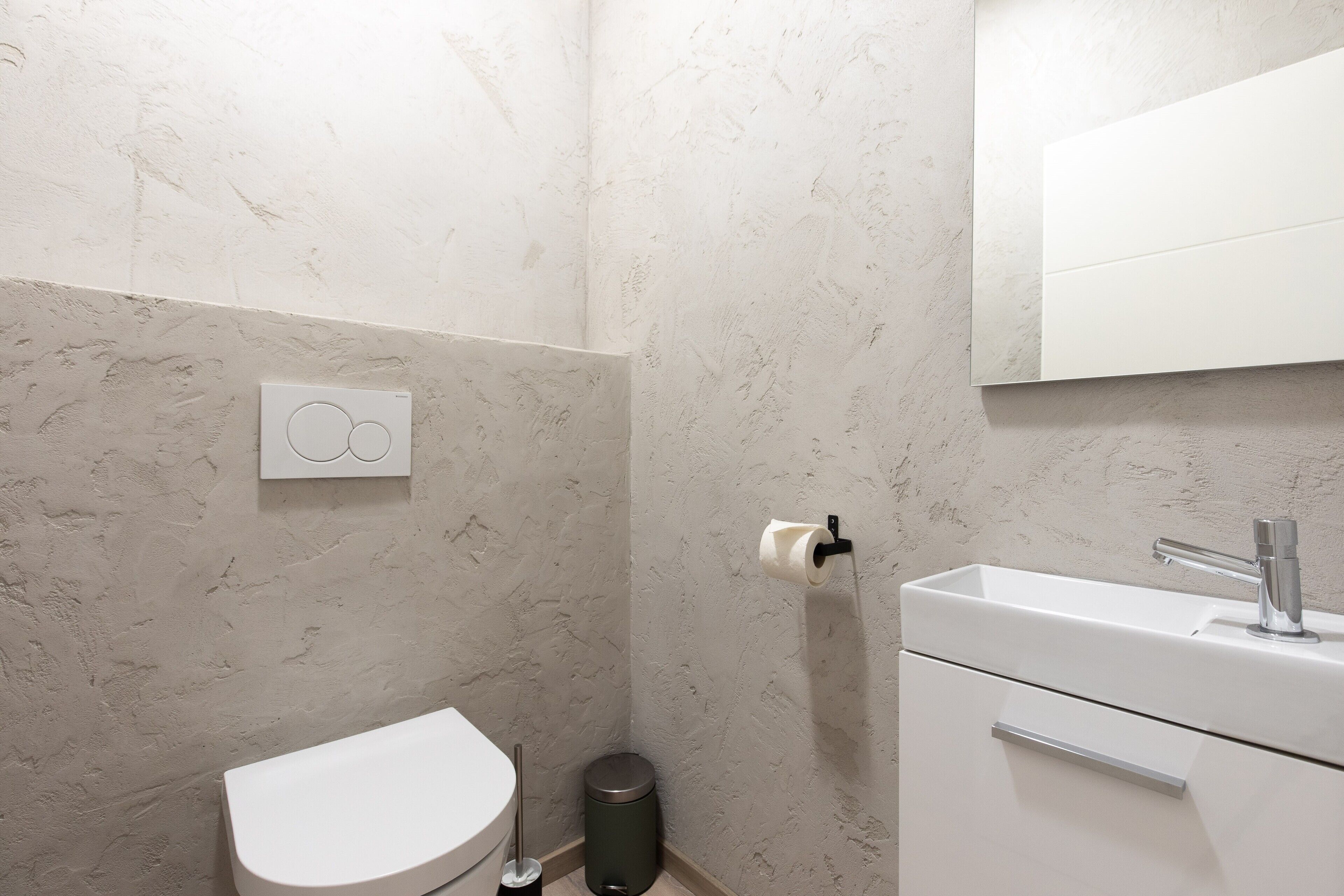 A bathroom with a toilet, sink, and mirror.