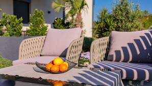A wicker sofa with cushions and a glass table with a bowl of oranges. - Villa LuiSole - Apartment °1 with heated saltwater pool, family-friendly (Krk)