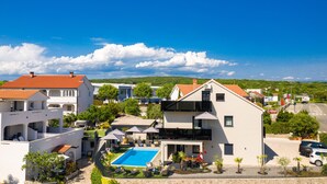 A modern two-story building with a swimming pool, surrounded by greenery and other residential buildings. - Villa LuiSole - Apartment °1 with heated saltwater pool, family-friendly (Krk)