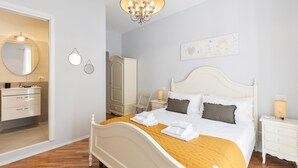 A neatly arranged bedroom with a bed, bedside tables, a wardrobe, and a chandelier.