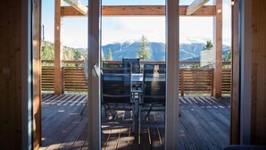 A wooden deck with a table and chairs, overlooking a mountainous landscape. - 47# mit IR-Sauna& Sprudelbad Innen by Interhome (Turracher Höhe)