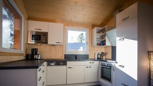 A modern kitchen with white cabinets, a microwave, a coffee maker, a sink, and a stove. - 47# mit IR-Sauna& Sprudelbad Innen by Interhome (Turracher Höhe)