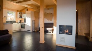 A modern interior with a kitchen, dining area, and fireplace. - 47# mit IR-Sauna& Sprudelbad Innen by Interhome (Turracher Höhe)