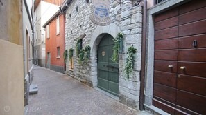 Un carrer empedrat estret amb un edifici de pedra que presenta una porta verda i un cartell amb la inscripció "Hotel for Holidays Torino in Riva Shop & Wine".