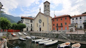 Uma área à beira-mar com uma igreja, barcos atracados e edifícios com varandas.