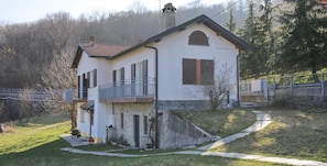 A two-story house with a balcony, a chimney, and a stone pathway leading to the entrance.