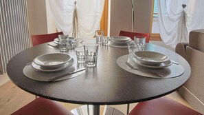 Une table de salle à manger ronde, avec deux assiettes, des couverts et des verres, le tout préparé pour deux personnes.