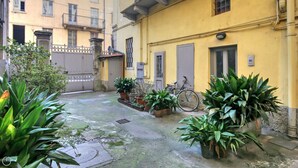 Ein Innenhof mit Blumentöpfen, einem Fahrrad und einem Gebäude mit Balkonen.