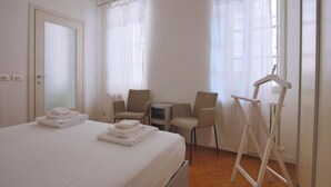 A hotel room with a bed, two chairs, a small table, a radiator, and a coat rack. - Bartolomeo de Benz - Torno (Torno)