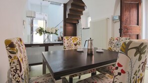 A dining area with a wooden table, floral-patterned chairs, a vase of flowers, and a coffee pot. - Bartolomeo de Benz - Torno (Torno)