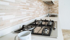 Una cucina moderna con piano cottura a gas, lavello in acciaio inossidabile e ripiano bianco.