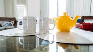 A table with two white mugs and a yellow teapot.