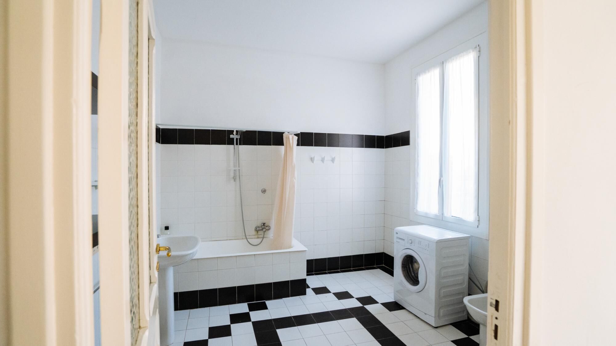 A small, clean bathroom with a shower, a toilet, and a washing machine.