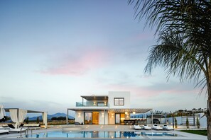 A modern two-story house with a swimming pool, outdoor seating, and a view of mountains. - Alma Villa, 2.000m2 Luxury Living (Rethymno)