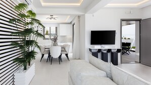Una sala de estar moderna con un sofá, comedor y televisor montado en la pared.
