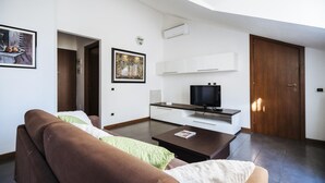 Una sala de estar moderna con un sofá marrón, una mesa de centro, un televisor de pantalla plana y un cuadro en la pared.