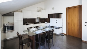 A modern kitchen with a dining area, including a stove, oven, and a dining table set for four.