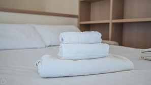 A neatly made bed with three rolled white towels and a wooden headboard. - Virgilio 2 - Villa Bice (Alassio)
