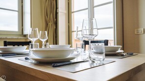 A dining table set with white plates, bowls, glasses, and a notebook. - Virgilio 2 - Villa Bice (Alassio)