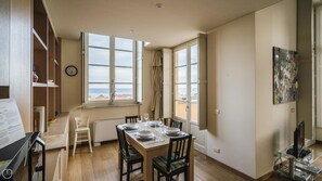 A dining area with a table set for four, a view of the sea through large windows, and a painting on the wall. - Virgilio 2 - Villa Bice (Alassio)