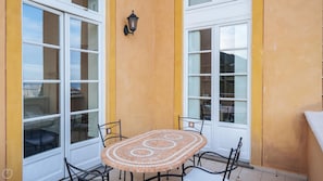 A patio with a tiled table and chairs, large windows, and a wall-mounted lantern.