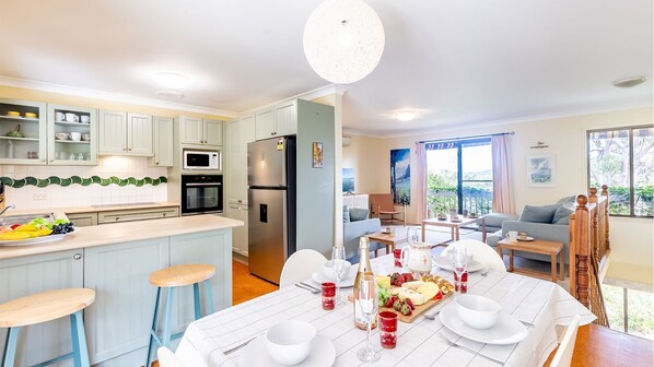 A modern kitchen with a central island, built-in appliances, and a dining area with a table set for a meal.