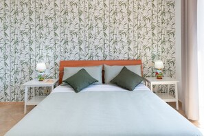 Une chambre d’hôtel avec un grand lit, deux tables de chevet et un papier peint à motifs de bambou.