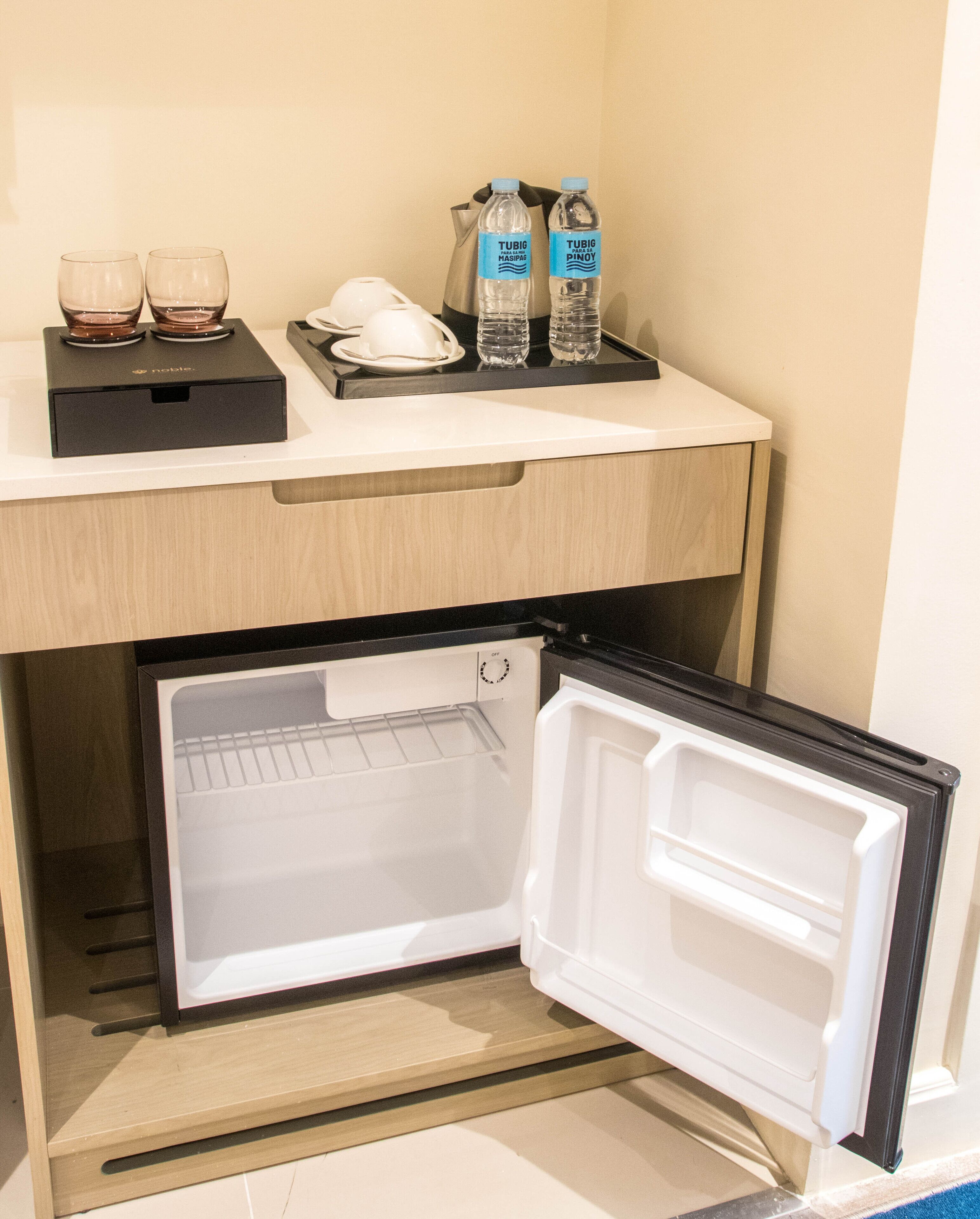 A compact refrigerator with a freezer compartment, a water dispenser, and a coffee maker.