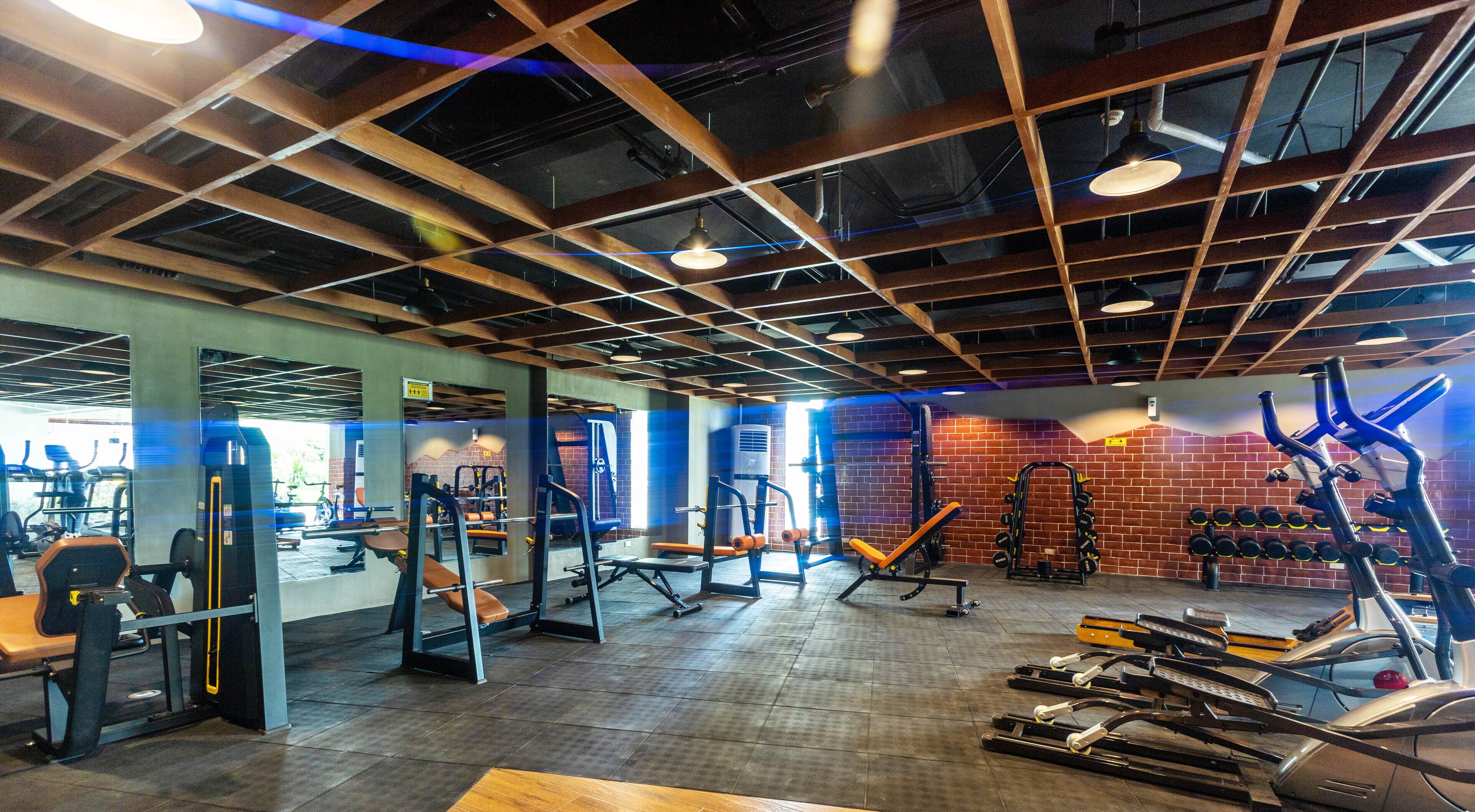 Une salle de sport équipée de divers appareils d’exercice, notamment des tapis de course, des appareils de musculation et des bancs.