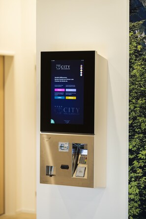 Quiosco digital de registro de entrada y salida con una pantalla que muestra un mensaje de bienvenida y opciones para registrarse y salir.