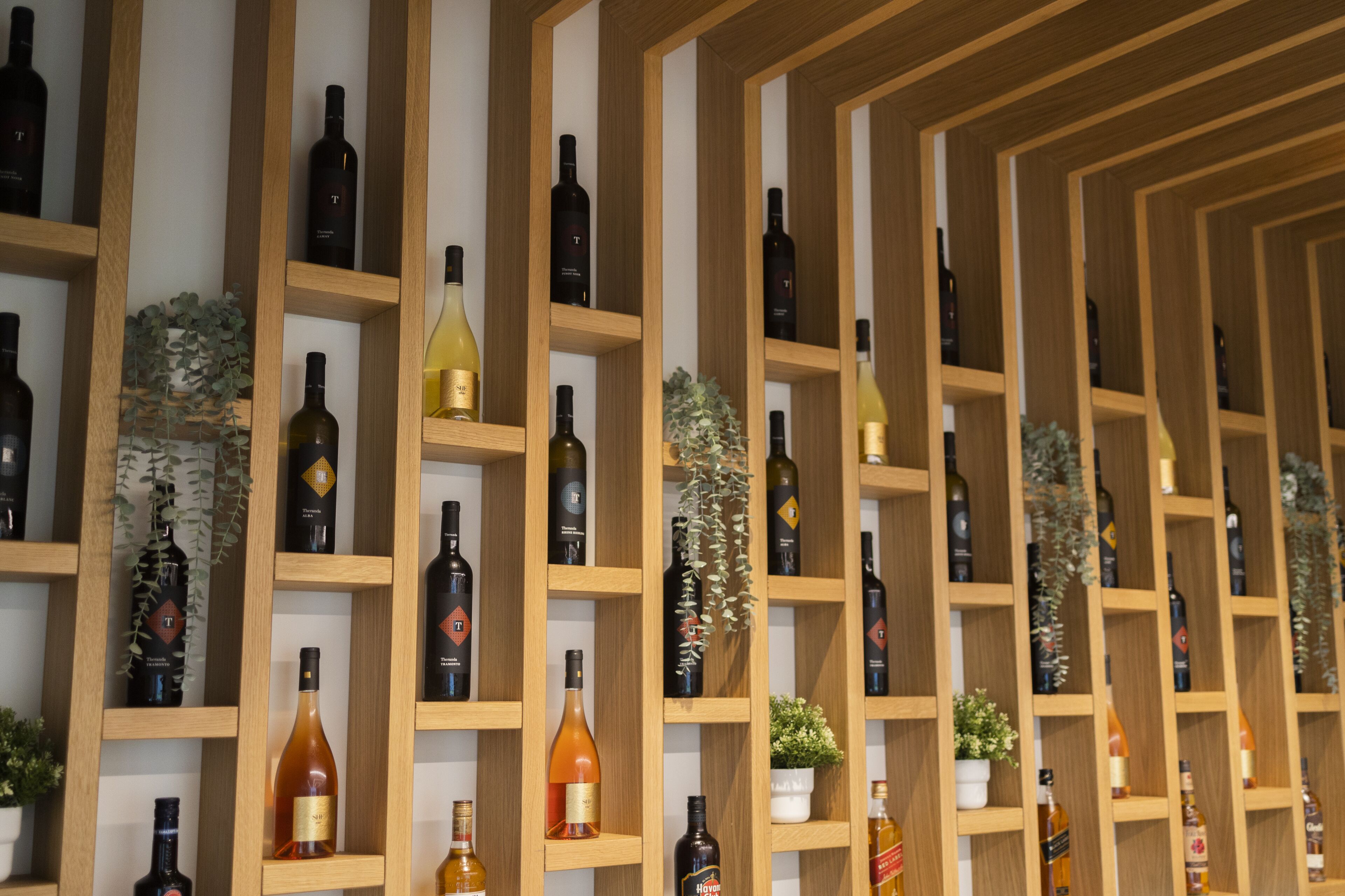 Una pared con botellas de vino dispuestas en estantes de madera.