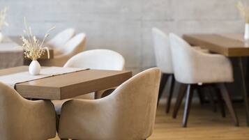 Interior de restaurante con un gran reloj de pared, decoración náutica y asientos modernos.