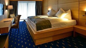 Una habitación de hotel con una cama grande, mesitas de noche, un escritorio y una silla.
