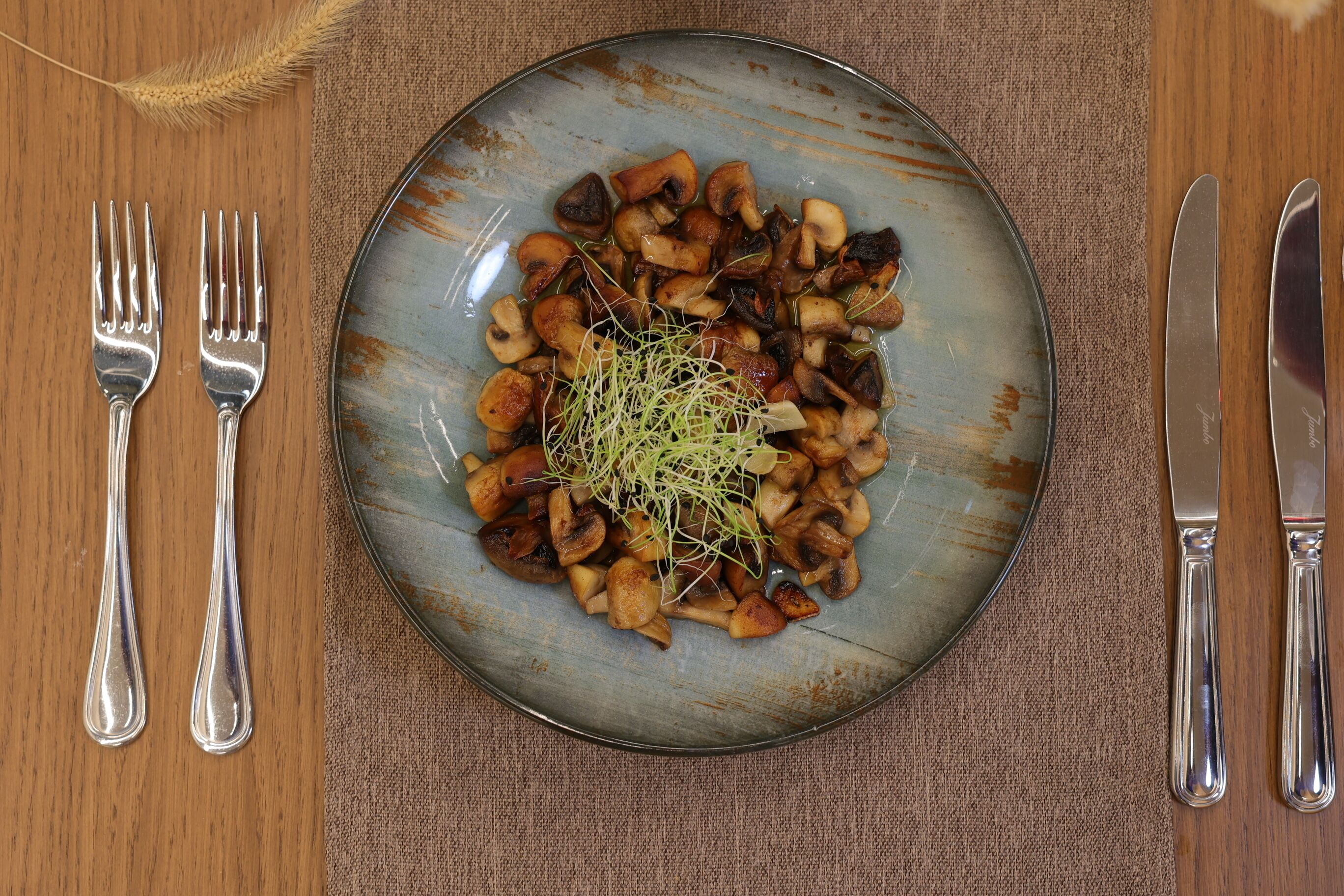 Un plato de champiñones salteados con guarnición de microgreens sobre un plato de cerámica rústica.