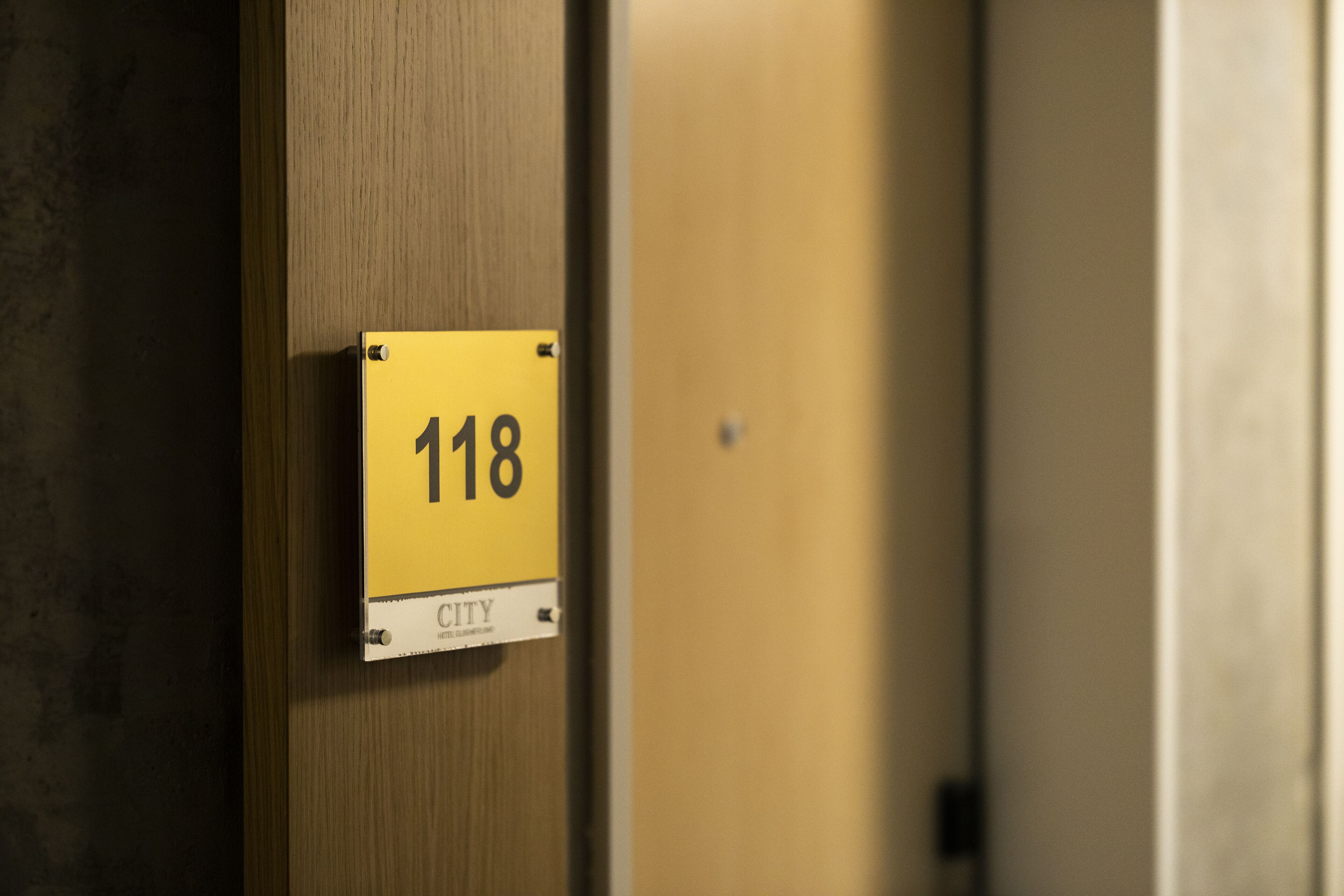 A yellow sign with the number 118 on a wooden door.