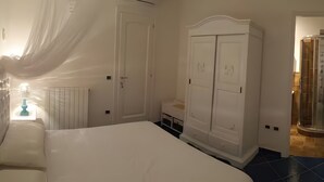 A bedroom with a bed, a wardrobe, and a bathroom with a shower.